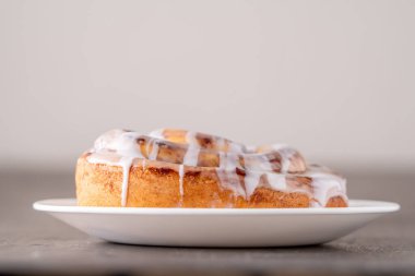 Kahverengi sıkıntılı masada büyük bir gurme kremalı tarçın rulosu.