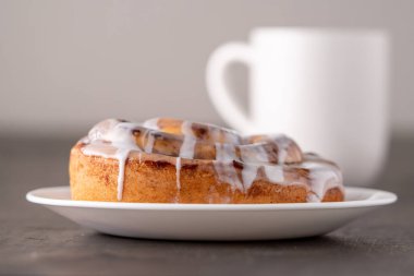 Kahverengi sıkıntılı masada büyük bir gurme kremalı tarçın rulosu.