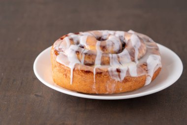 Kahverengi sıkıntılı masada büyük bir gurme kremalı tarçın rulosu.