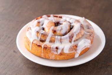 Kahverengi sıkıntılı masada büyük bir gurme kremalı tarçın rulosu.