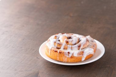 Kahverengi sıkıntılı masada büyük bir gurme kremalı tarçın rulosu.
