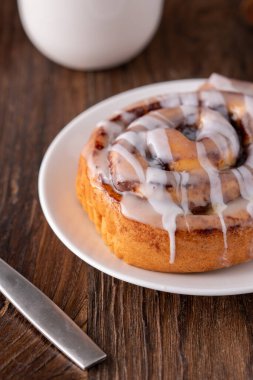 Kahverengi sıkıntılı masada büyük bir gurme kremalı tarçın rulosu.