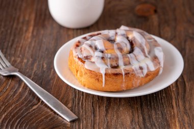 Kahverengi sıkıntılı masada büyük bir gurme kremalı tarçın rulosu.