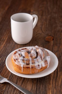 Kahverengi sıkıntılı masada büyük bir gurme kremalı tarçın rulosu.