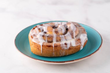 Büyük gurme şekerli tarçınlı rulo mermer masada.