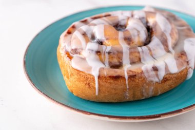 Büyük gurme şekerli tarçınlı rulo mermer masada.