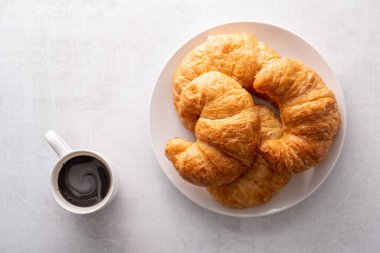 Beyaz tabakta gevrek gevrek kruvasan rulosu ve sıkıntılı bir masa.