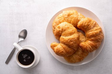 Beyaz tabakta gevrek gevrek kruvasan rulosu ve sıkıntılı bir masa.