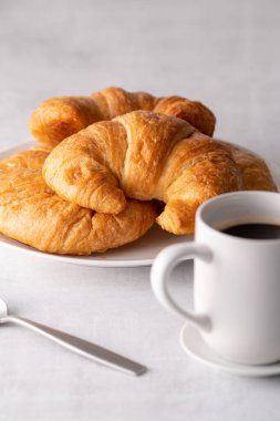 Beyaz tabakta gevrek gevrek kruvasan rulosu ve sıkıntılı bir masa.