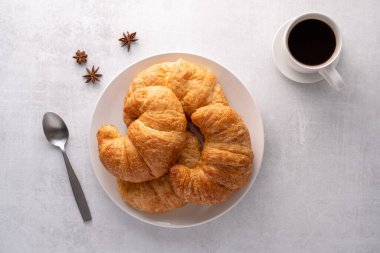 Beyaz tabakta gevrek gevrek kruvasan rulosu ve sıkıntılı bir masa.