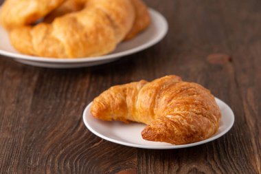 Beyaz tabakta çıtır çıtır çıtır Crescent rulo ve sıkıntılı ahşap masa.