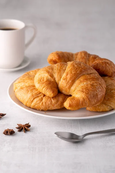 stock image Warm crispy flaky croissant roll on white plate and distressed table