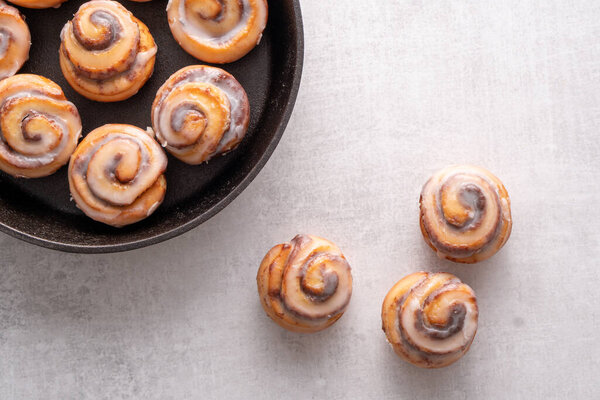 Homemade baked cinnamon rolls baked in an iron skillet with icing