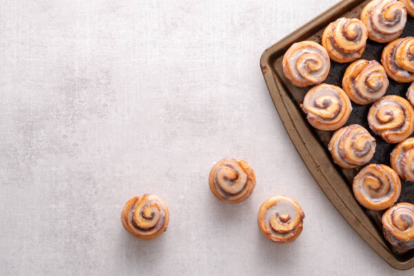 Homemade baked cinnamon rolls baked in a cookie sheet with icing.