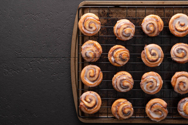 Homemade baked cinnamon rolls baked in a cookie sheet with icing.