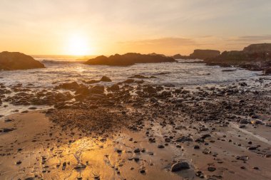 Pasifik Okyanusu 'nun çekilmekte olan gelgiti üzerinde sıcak gün batımı