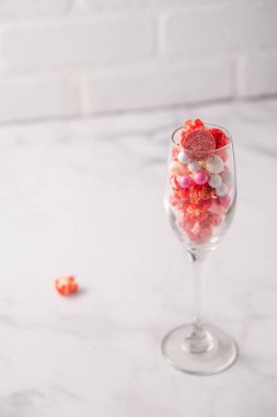 Renkli kırmızı ve pembe patlamış mısır ve şampanya kadehinde karışık şekerler..