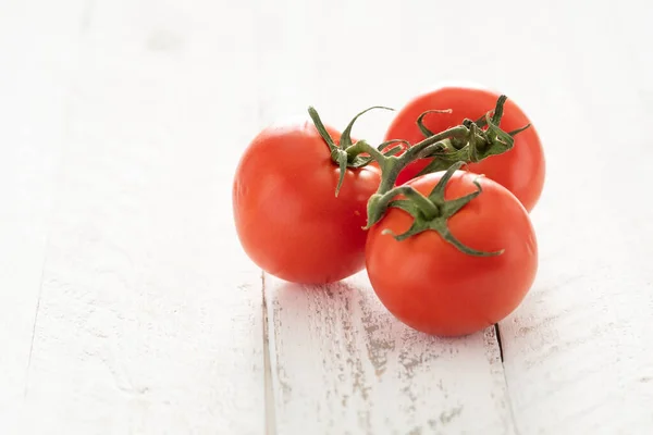 Stock image red vine ripe tomatoes on white rustic table