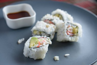 Gövde içinde soya sosunun yanında yengeç etli maki resmi.