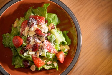 Masadaki kasede servis edilen taze salata, marul ve çilek ile yakından bakın.