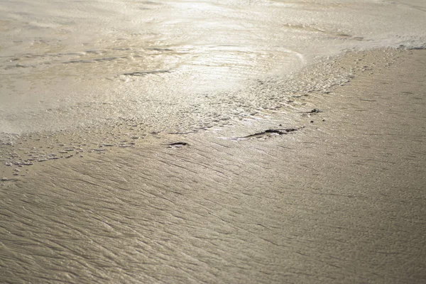 明るい日差しの中での砂浜のぬれたラフな質感の背景 — ストック写真