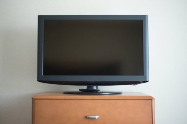 Düz ekran TV seti ahşap bir şifoniyerin üstünde.