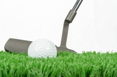 Siyah golf sopasıyla uzun yeşil çimlerin üzerinde oturan bir golf topu..