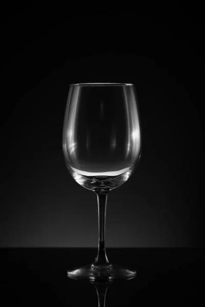 stock image One standing empty upright wineglass black background and surface