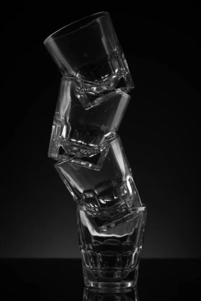 Gestapelte Klarglas Schnapsgläser Schwarzer Hintergrund Reflektierende Oberfläche Und Umständliche Anordnung — Stockfoto