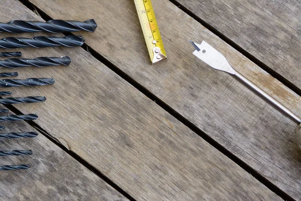 Power drill tape measure with many drill bits on an old wood deck.