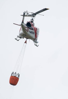 Bir Cal Fire helikopteri Berryessa Gölü, Kaliforniya 'da su kovasıyla uçuyor.