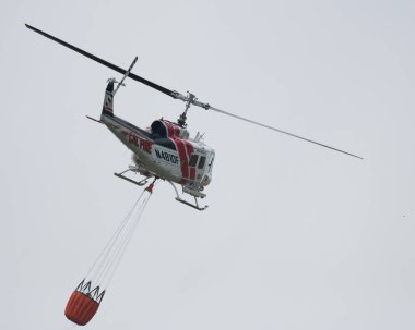Bir Cal Fire helikopteri Berryessa Gölü, Kaliforniya 'da su kovasıyla uçuyor.