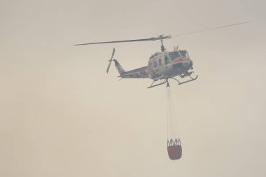 Bir Cal Fire helikopteri Berryessa Gölü, Kaliforniya 'da su kovasıyla uçuyor.