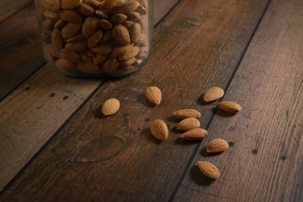 Scattered Almonds Wood Table Large Jar — Stock Photo, Image