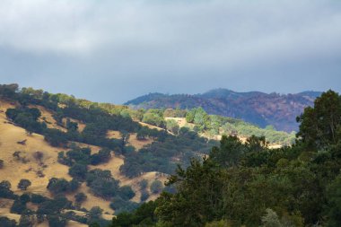 Bulutların arasından gelen ışık dağ yüzünü aydınlatıyor. Berryessa California gölü.