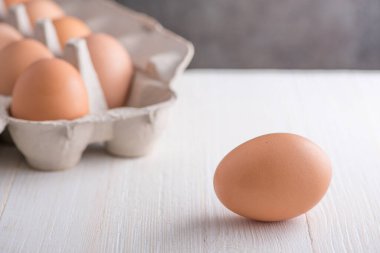 Beyazlatılmış ahşap masa yüzeyinde kahverengi yumurta kutusu