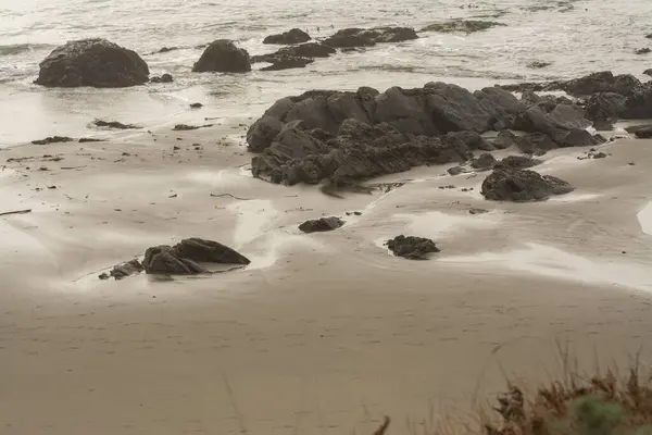 Вид Тихий Пляж Піском Темними Каменями Стирчать Води Землі — стокове фото
