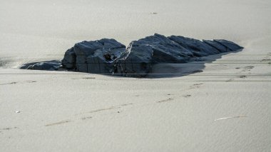 Kaya kayaları kumsaldaki kumlarla ortaya çıkar.