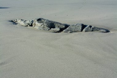 Kaya kayaları kumsaldaki kumlarla ortaya çıkar.
