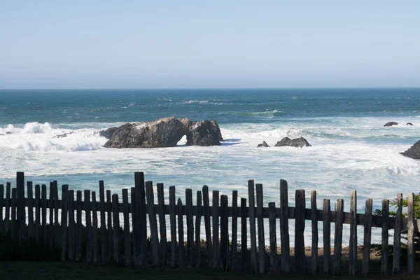 青い空を背景に 海岸の柵や日差しの中の荒波の白い波の風景 — ストック写真