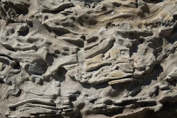 stock image Abstraction of layers of old rock formation with rough surface in bright sunlight 