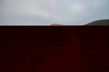 Bulutlu bir günde küçük tepelere açılan kumlu yola bak 