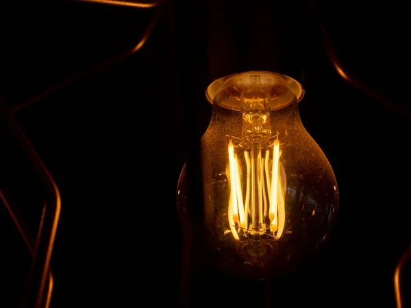 stock image Vintage incandescent light bulb filament on black, close up shot