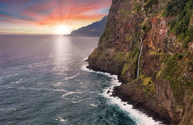 Madeira Adası - Miradouro do Veu da Noiva 'dan şelale manzaralı Atlantik okyanusu üzerinde dramatik gün doğumu