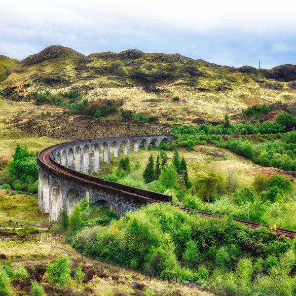 Glenfinnan Viaduct, Scotland. Travel tourist destination in Europe. Old historical steam train riding on film scene famous Harry Potter viaduct bridge. Highlands, mountains, outdoor background.