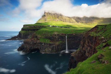 Gasadalurron köyü yakınlarındaki Faroe Adaları şelalesi Mlafossur Vagar Adası. Yeşil dağ manzarası.