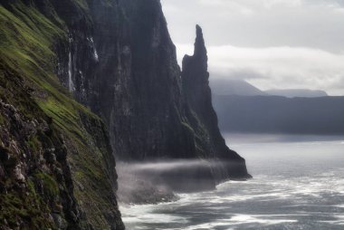 Rocky kıyı şeridi ve Atlantik Okyanusu 'ndaki Vagar, Faroe Adaları' nda Trol Kadın Parmağı olarak bilinir.. 