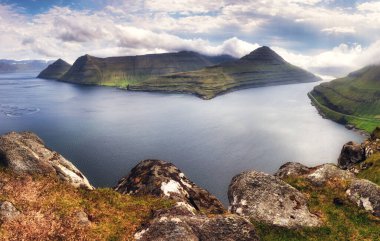 Okyanusla kaplı dağ manzarası. Faroe Adaları 'ndaki Eysturoy Adası' ndaki Funningur fiyordunun üzerinde sis var..