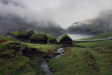 Saksun Village, Streymoy Island, Faroe islands. Old stone houses with a grass (turf) roof. Tourist sightseeing in green valley clipart