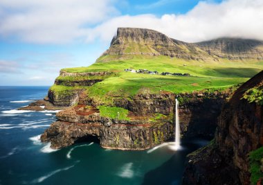 Faroe Adaları şelalesi Mafossur. Gasadalurron köyü yakınlarında. Ada Vgar. Yeşil dağ manzarası.